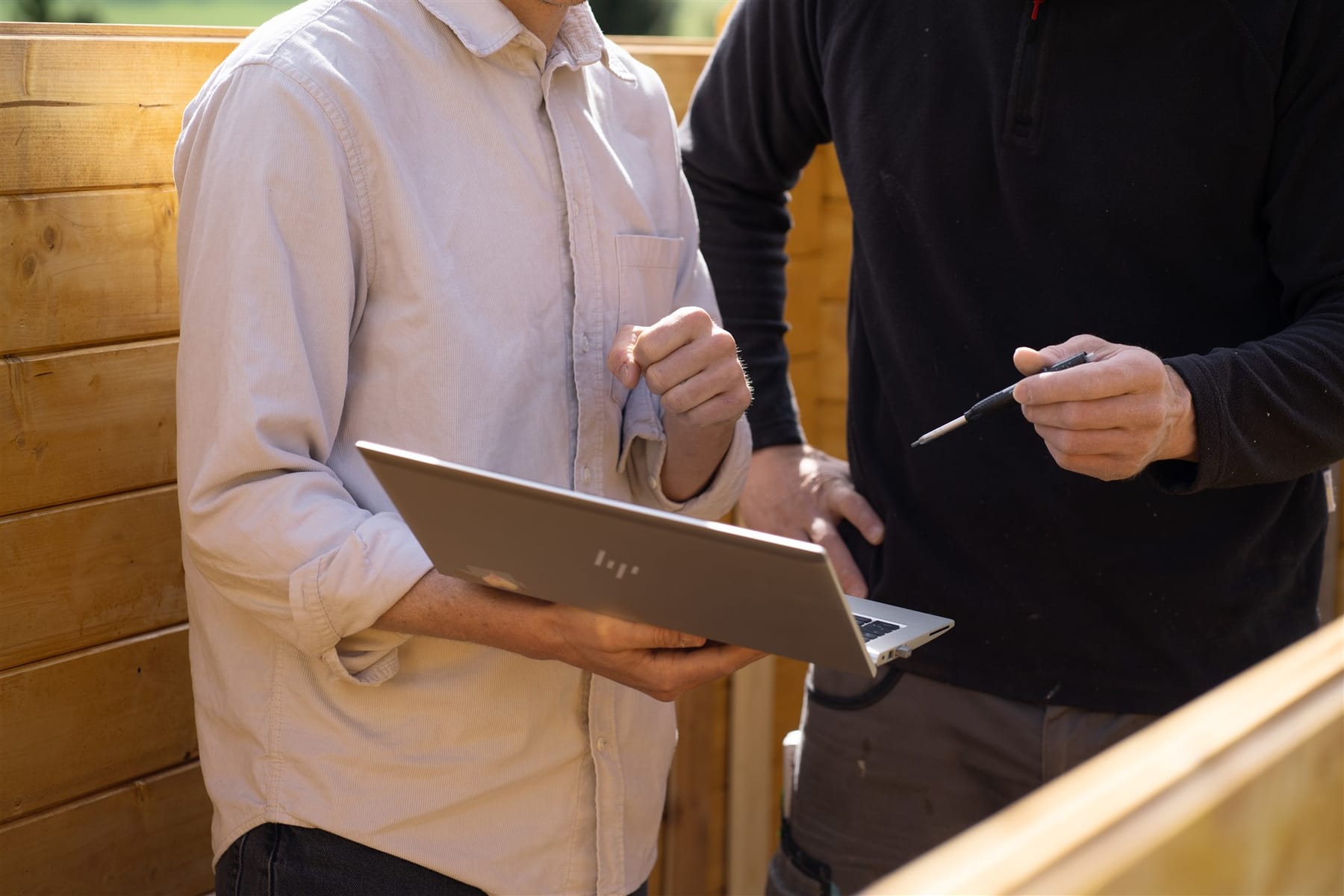 Besprechung im Betrieb: Laptop und Bleistift vor einer Holzwand